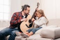 happy father with adorable smiling little daughter playing guitar together