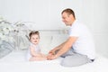 Happy father and baby daughter talking or playing on a white bed at home, family, father`s day Royalty Free Stock Photo