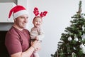 Happy father with baby girl playing at home with reindeer diadem. Christmas concept