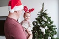 Happy father with baby girl playing at home with reindeer diadem. Christmas concept