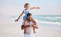 Happy father carrying his daughter on his shoulders while walking along the beach. Adorable little girl stretching out Royalty Free Stock Photo