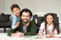 happy father with cute little kids smiling at camera while drawing with colored pencils