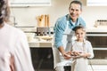 happy father with daughter showing plate with pancakes to mother