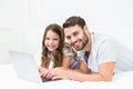 Happy father and daughter using laptop on bed Royalty Free Stock Photo