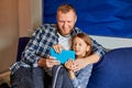 Happy father with daughter using tablet computer in living room, at sofa at home Royalty Free Stock Photo