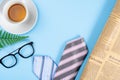 Happy Father Day background concept with blue and pink necktie, glasses, newspaper, leaf and cup of tea on blue background with
