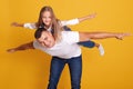 Happy father giving his daughter piggyback ride, daddy and child having fun together, models posing islolated over yellow Royalty Free Stock Photo