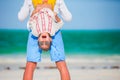 Happy father and his adorable little daughter at tropical beach having fun. Kid hanging upside down in the hands of her Royalty Free Stock Photo