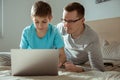 Happy father with his little son playing computer games with laptop together in bedroom Royalty Free Stock Photo