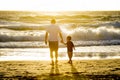 Happy father holding hand of little son walking together on the beach with barefoot Royalty Free Stock Photo