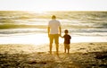 Happy father holding hand of little son walking together on the beach with barefoot Royalty Free Stock Photo