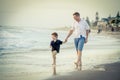 Happy father holding hand of little son walking together on the beach with barefoot Royalty Free Stock Photo