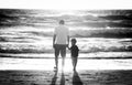 Happy father holding holding hand of little son walking together on the beach with barefoot Royalty Free Stock Photo