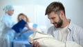 Happy father holding newborn child during nurse explaining wife postnatal care Royalty Free Stock Photo