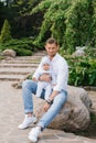 Happy father holds his baby son in his arms in a spring blooming park, sitting in the park Royalty Free Stock Photo