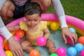 happy father and infant baby girl playing water with colorful plastic balls in inflatable pool Royalty Free Stock Photo