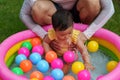 happy father and infant baby girl playing water splashing with colorful plastic balls in inflatable pool Royalty Free Stock Photo