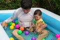 happy father and infant baby girl playing water splashing with colorful plastic balls in inflatable pool Royalty Free Stock Photo