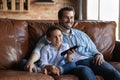 Happy father with little son watching tv, sitting on couch Royalty Free Stock Photo