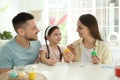 Happy father, mother and daughter painting Easter eggs at table Royalty Free Stock Photo
