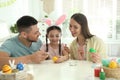 Happy father, mother and daughter painting Easter eggs at table Royalty Free Stock Photo