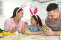 Happy father, mother and daughter painting Easter eggs at table Royalty Free Stock Photo