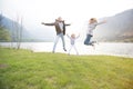 Happy father, mother and little girl jumping near lake on a beautiful sunny day Royalty Free Stock Photo