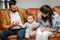 Happy father, mother and little son are playing on sofa in living room. Child care and parenting Royalty Free Stock Photo