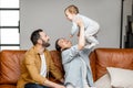 Happy father, mother and little son are playing on sofa in living room. Child care and parenting Royalty Free Stock Photo