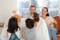 Happy father and mother watching cute siblings puppet show.