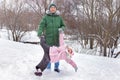 A happy father is playing with his daughter, rolling her in the park in winter. Family rest Royalty Free Stock Photo