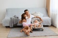 Happy father playing with his daughters, little girl hugging dad, man wearing white casual style T-shirt and jeans short sitting Royalty Free Stock Photo