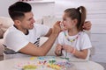 Happy father putting handmade beaded jewelry on his cute daughter at home Royalty Free Stock Photo