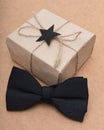 Beautiful retro style gift box and black bow tie on brown background. Fathers day still life.