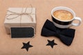 Father`s Day Background. Cup of coffee, beautiful present and black bow tie on brown background flat lay. Fathers day.