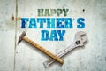 Happy father`s day background. Inscription written on a concrete wall. Tools for repair. Adjustable wrench, hammer, screwdriver