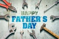 Happy father`s day background. Inscription written on a concrete wall. Tools for repair. Adjustable wrench, hammer, screwdriver Royalty Free Stock Photo