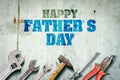 Happy father`s day background. Inscription written on a concrete wall. Tools for repair. Adjustable wrench, hammer, screwdriver