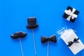 Happy Father`s day cards. Black tie, mustache and hat cookies and gift. Blue background top view Royalty Free Stock Photo