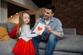 Happy father\'s day! Child daughter congratulates dad and gives him postcard. Daddy and girl, kissing, smiling and hugging