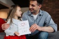 Happy father\'s day! Child daughter congratulates dad and gives him postcard. Daddy and girl, kissing, smiling and hugging