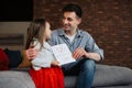 Happy father\'s day! Child daughter congratulates dad and gives him postcard. Daddy and girl, kissing, smiling and hugging.