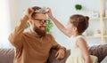 Happy father`s day! child daughter in crown does makeup to daddy Royalty Free Stock Photo