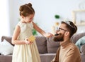 Happy father`s day! child daughter in crown does makeup to daddy Royalty Free Stock Photo