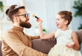 Happy father`s day! child daughter in crown does makeup to daddy Royalty Free Stock Photo