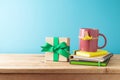 Happy Father\'s day concept with colorful coffee cup, mustache, notebook and gift box on wooden table over blue background