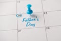 Happy Father`s day concept. Cropped close up view photo of light blue pushpin attached to calendar with congrats text