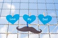 The heart paper written that FATHER and paper mustache on the wire mesh, the blue sky background