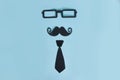 Happy father`s day flat lay. Decorative man mustache, black glasses and bow-tie on a light blue wooden background. top view Royalty Free Stock Photo