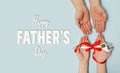 Happy father`s day. Greeting card. Gift wrench with a red ribbon in hands of daughter and father on blue background. Banner